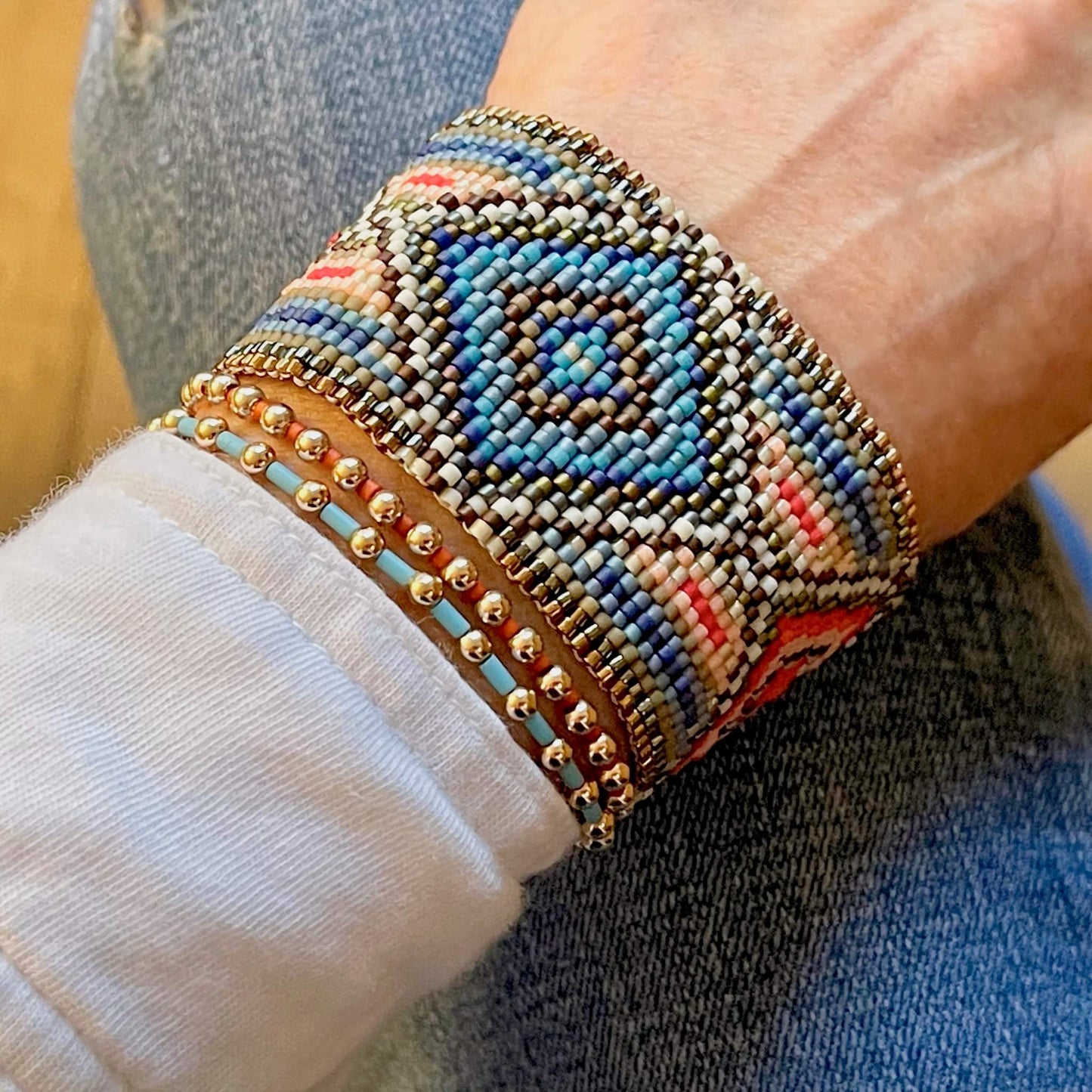 Hand woven peyote beaded bracelet in turquoise & coral diamond pattern, stacked with gold ball & seed bead stretch bracelets.