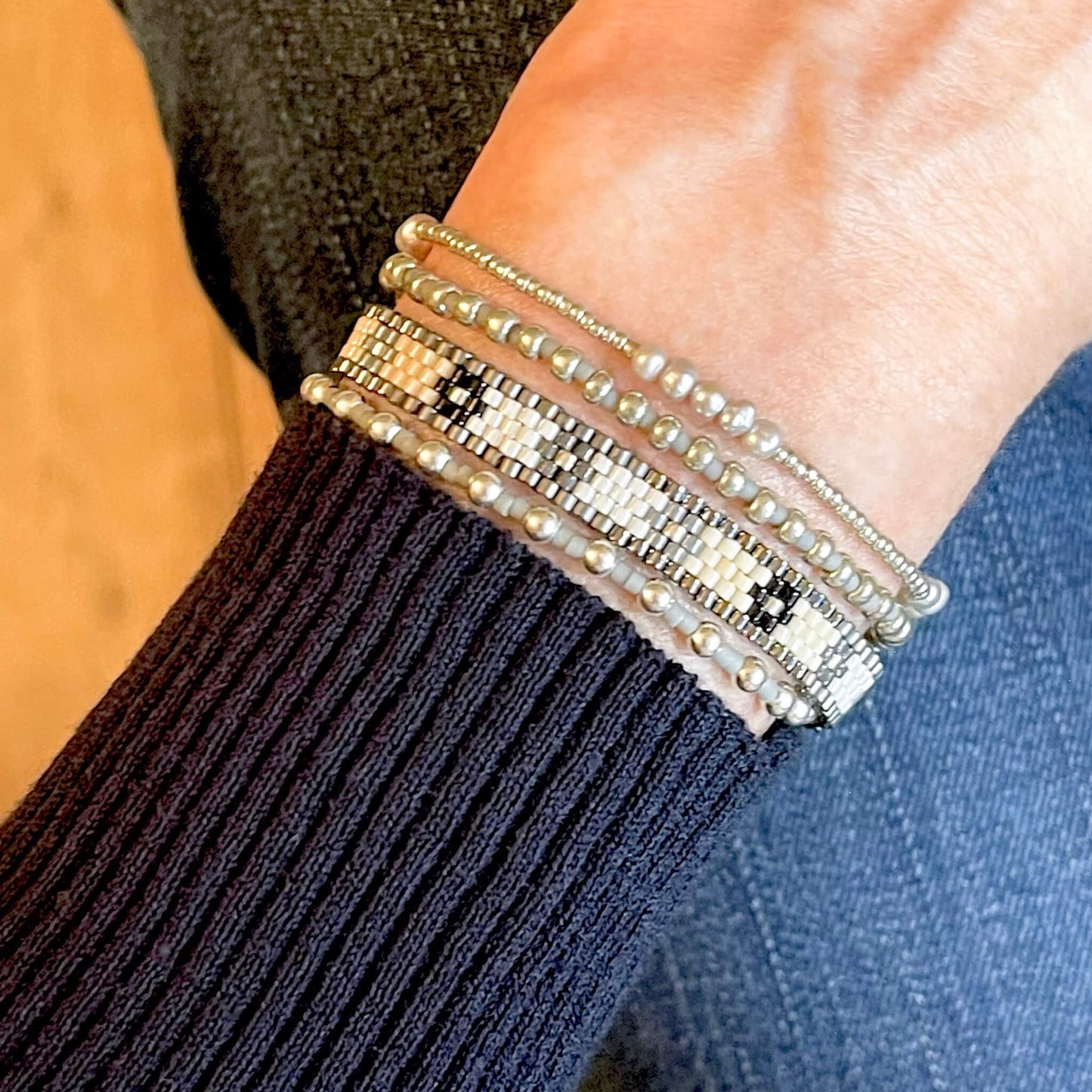 White, black, and silver flower beaded bracelet stack of 4 with one woven band and 3 stretch bracelets with silver beads and freshwater pearls.