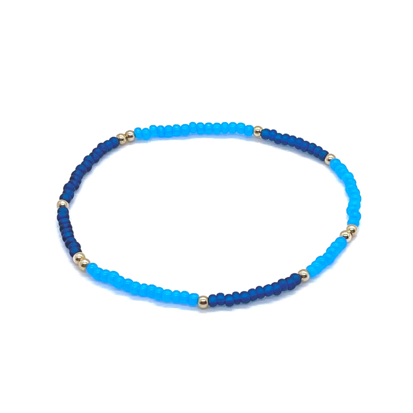 Beaded anklet with bright blue and dark blue color bars of seed beads with gold fill balls. Stretchy anklet handmade in NYC.