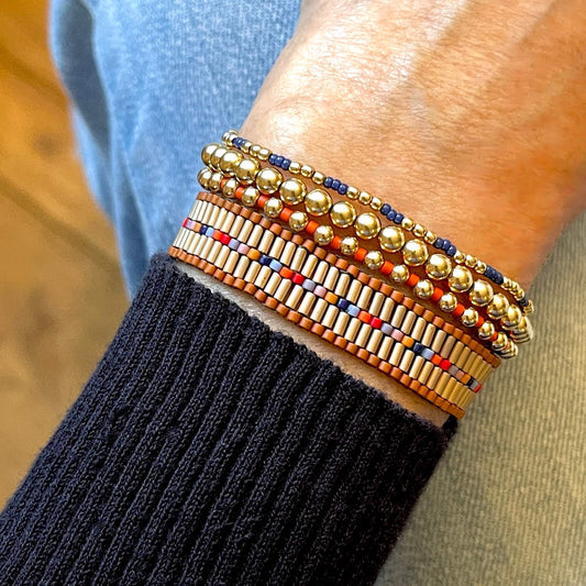 Bugle bead bracelet with a brown border and pops of color. Coordinating gold ball stretch bracelets with orange and blue glass seed beads.