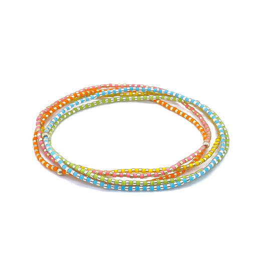 Dainty ankle bracelets with bright miyuki delica seed beads with gold and silver tone accents on elastic stretch cord.