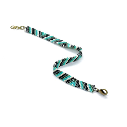 Hand beaded men’s woven peyote beaded bracelet with clasp and aqua, green, black, & white stripes and triangles.