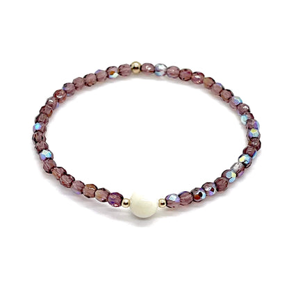 Amethyst crystal bracelet with a mother-of-pearl center bead and small gold accent beads.
