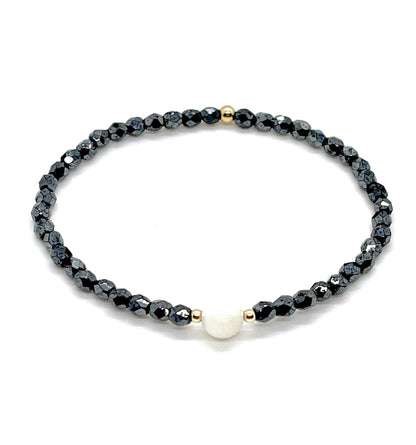 Black crystal bracelet with mother-of-pearl center bead and small gold accent beads.