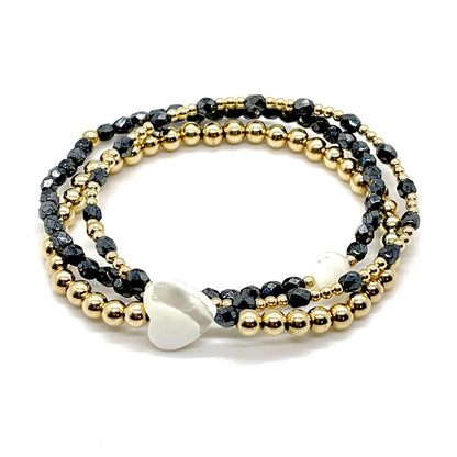 Black, crystal, and gold bracelet stack of 3. Womens handmade stretch bracelets with round and heart mother-of-pearl-beads.