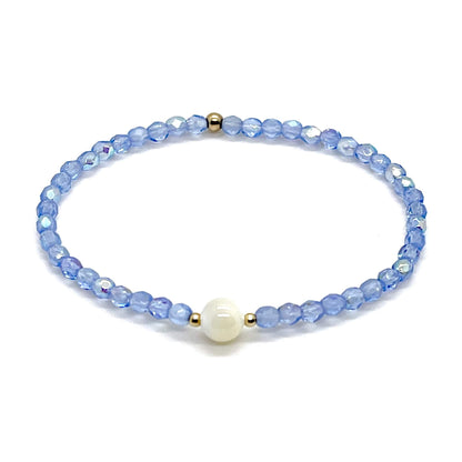 Blue crystal bracelet with a mother-of-pearl center bead and small gold accent beads.