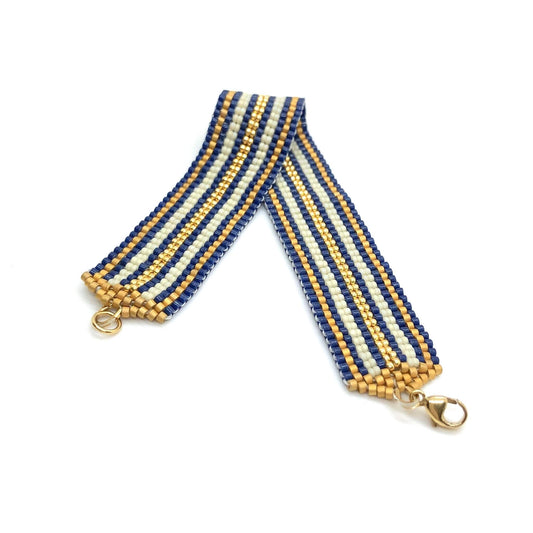 Flat beaded bracelet with blue, white and, gold glass seed beads in a striped pattern. Nautical color scheme.