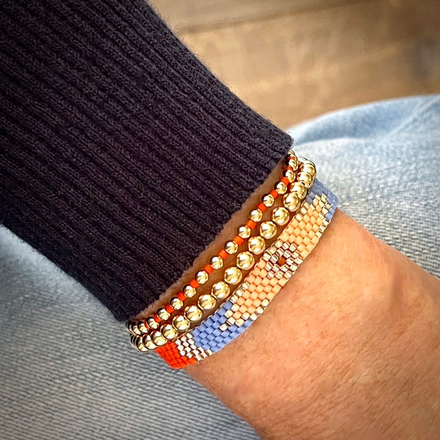 Blue, orange, and gold handmade beaded bracelet set with a woven peyote band and two gold ball stretch bracelets.