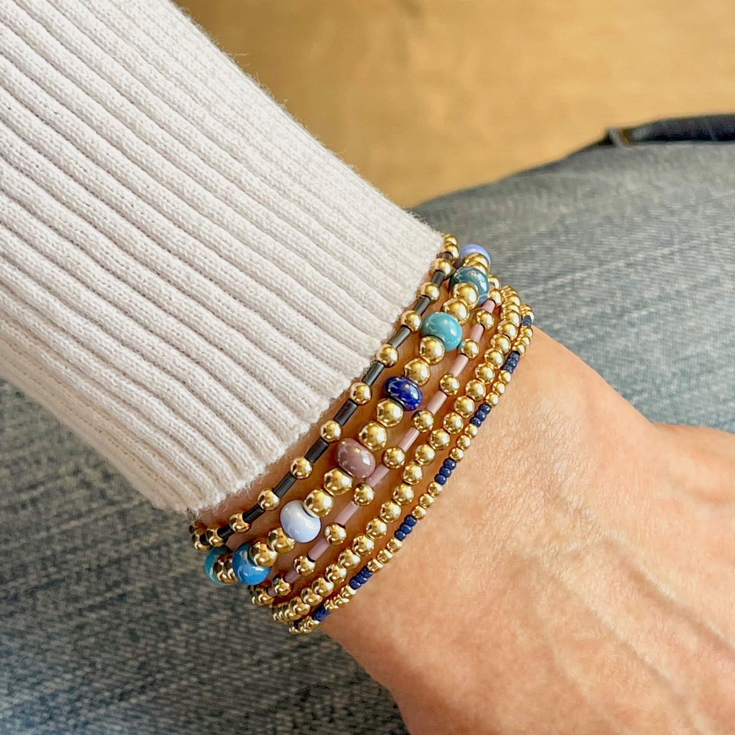 Gold bead bracelet stack of 5 stretch bracelets with blue and purple accent beads.