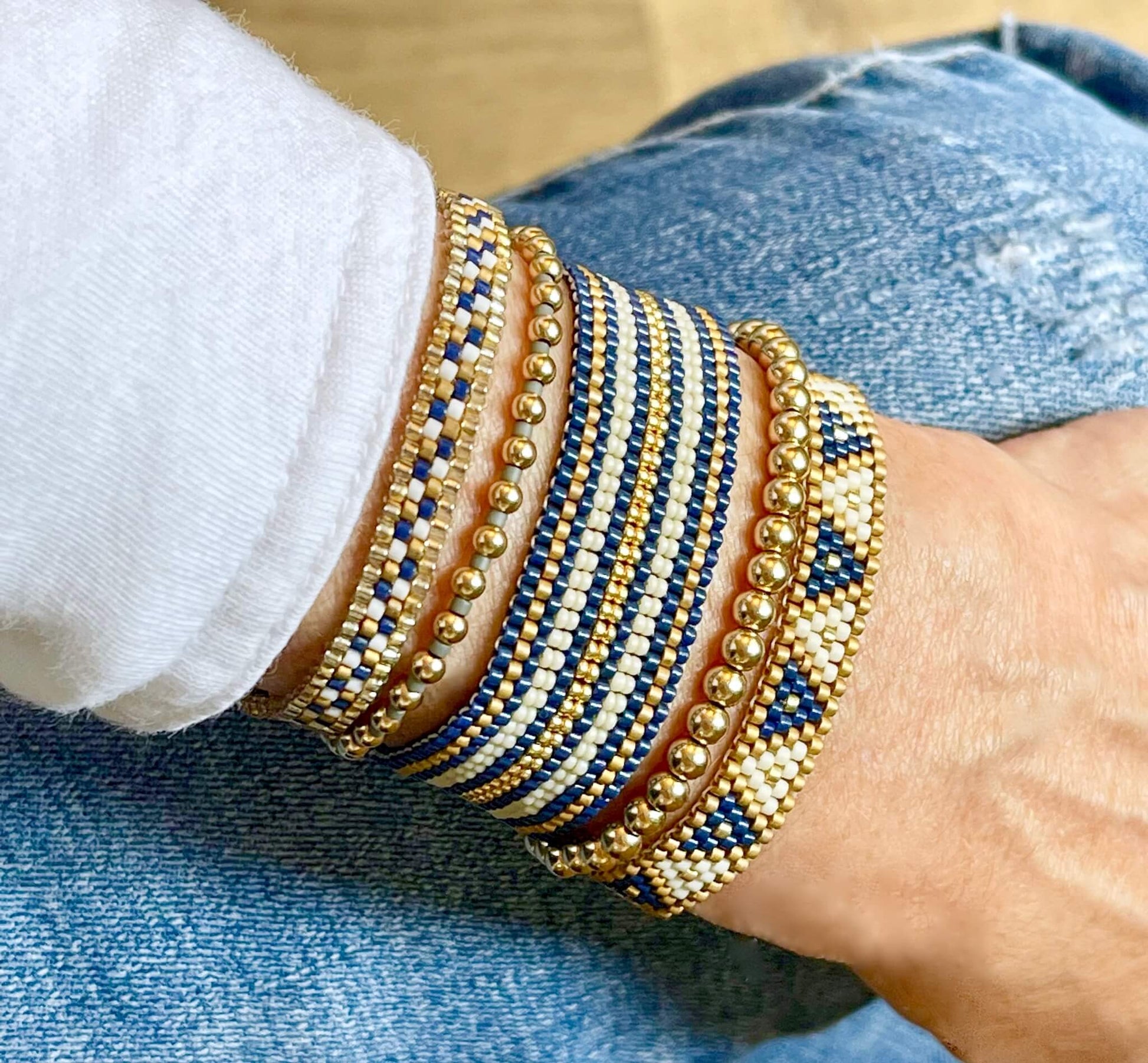 Gold ball bead bracelets stacked with flat beaded bracelets. Preppy nautical colors and patterns. Navy, white, and gold stripes and triangles.