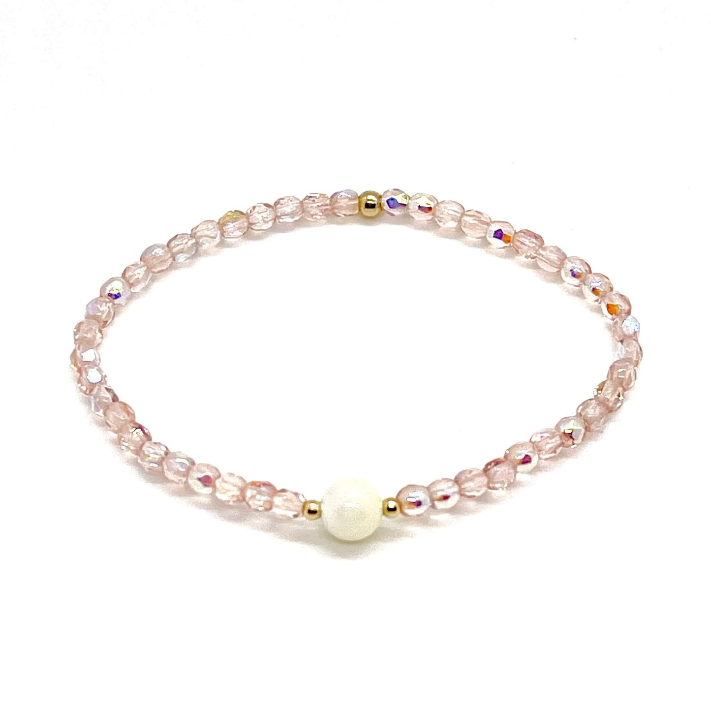 Blush-rose crystal bracelet with a mother-of-pearl center bead and small gold accent beads.