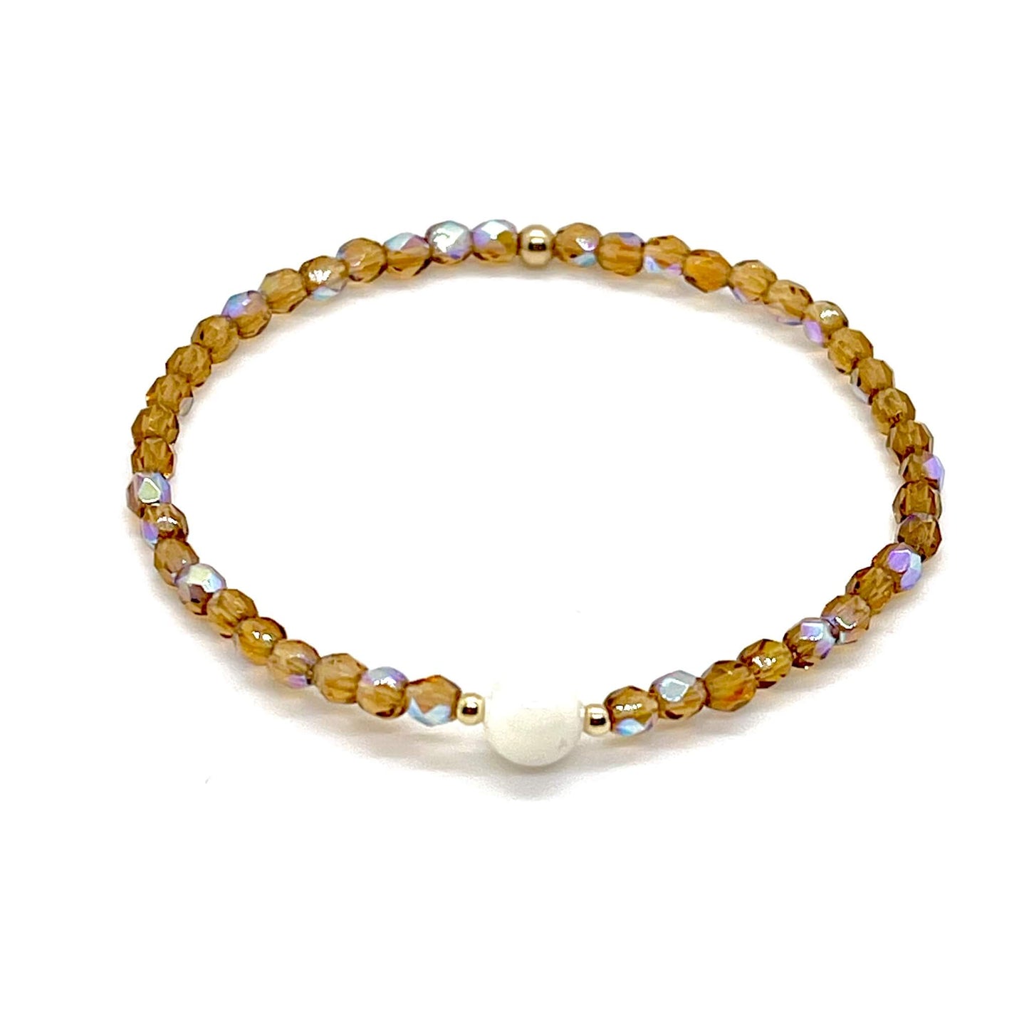 Brown crystal bracelet with a mother-of-pearl center bead and small gold accent beads.