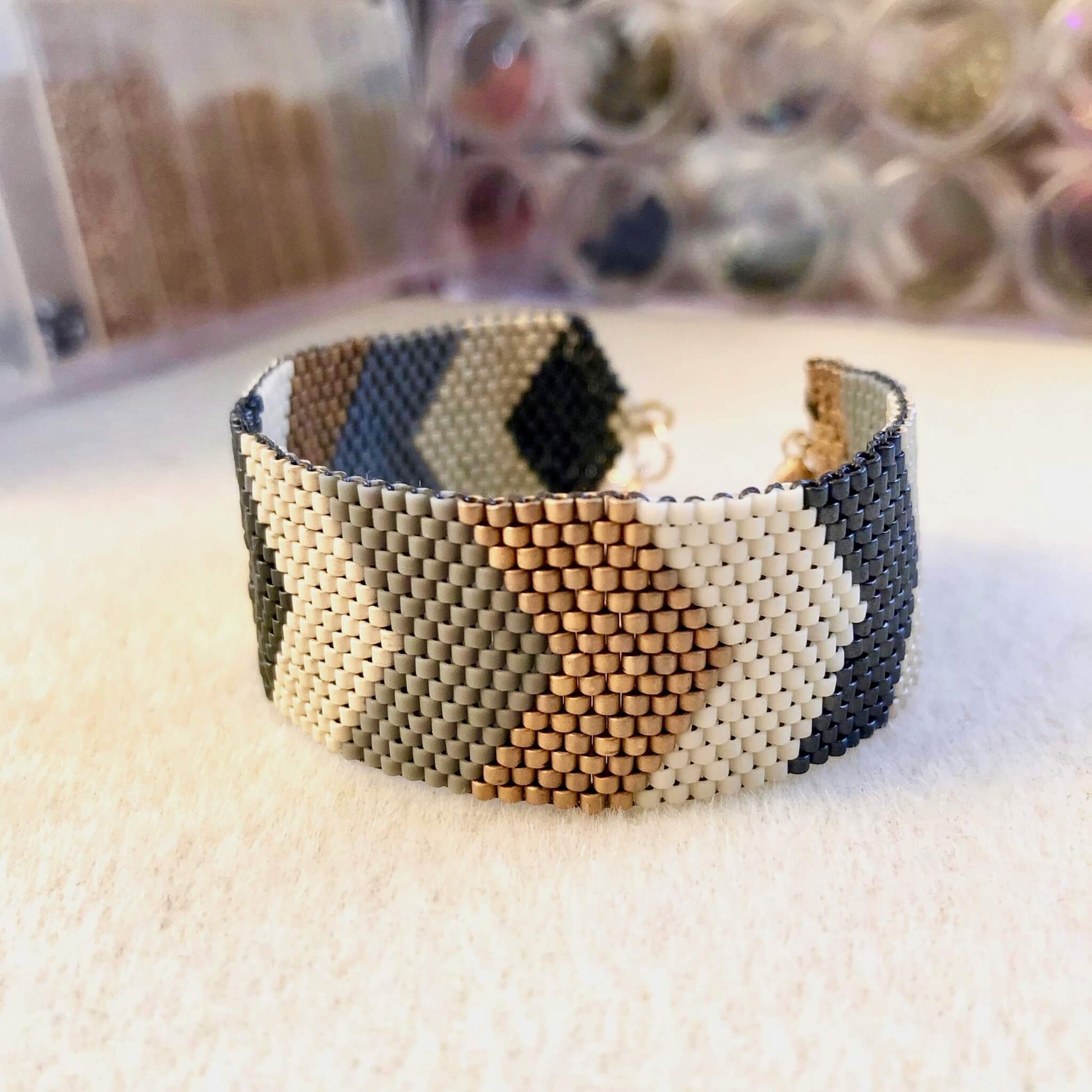 Cuff bead bracelet in chevron pattern with tan, slate, gray, silver, and bronze beads.