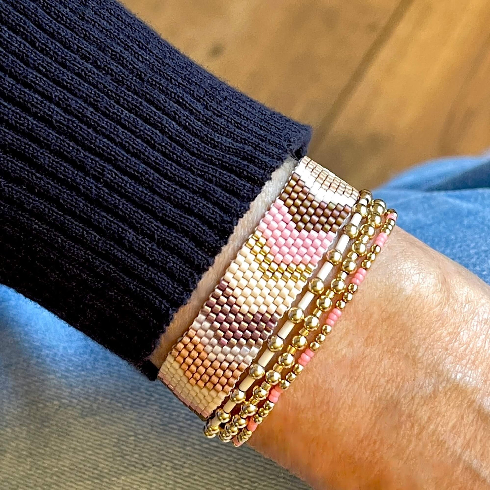 Chevron bracelet with pink, white, and gold seed beads and 3 gold ball stretch bracelets with 14K gold filled beads.