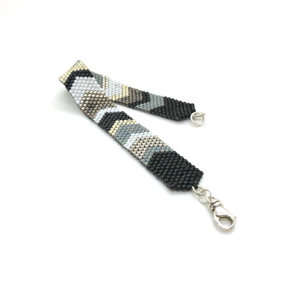 Sleek and modern metallic silver, black and gray hand woven beaded bracelet wristband with chevron-inspired details.