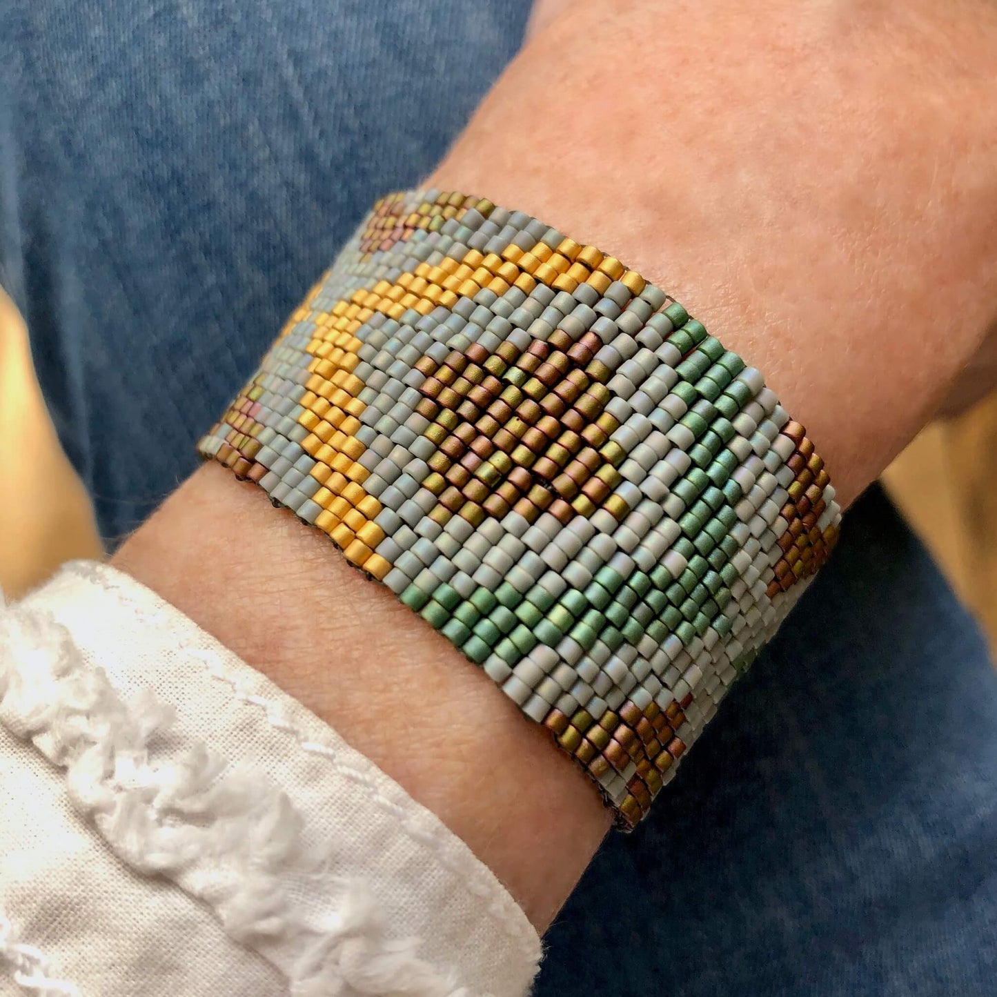 Cuff bracelet with green, grey, and gold seed beads.