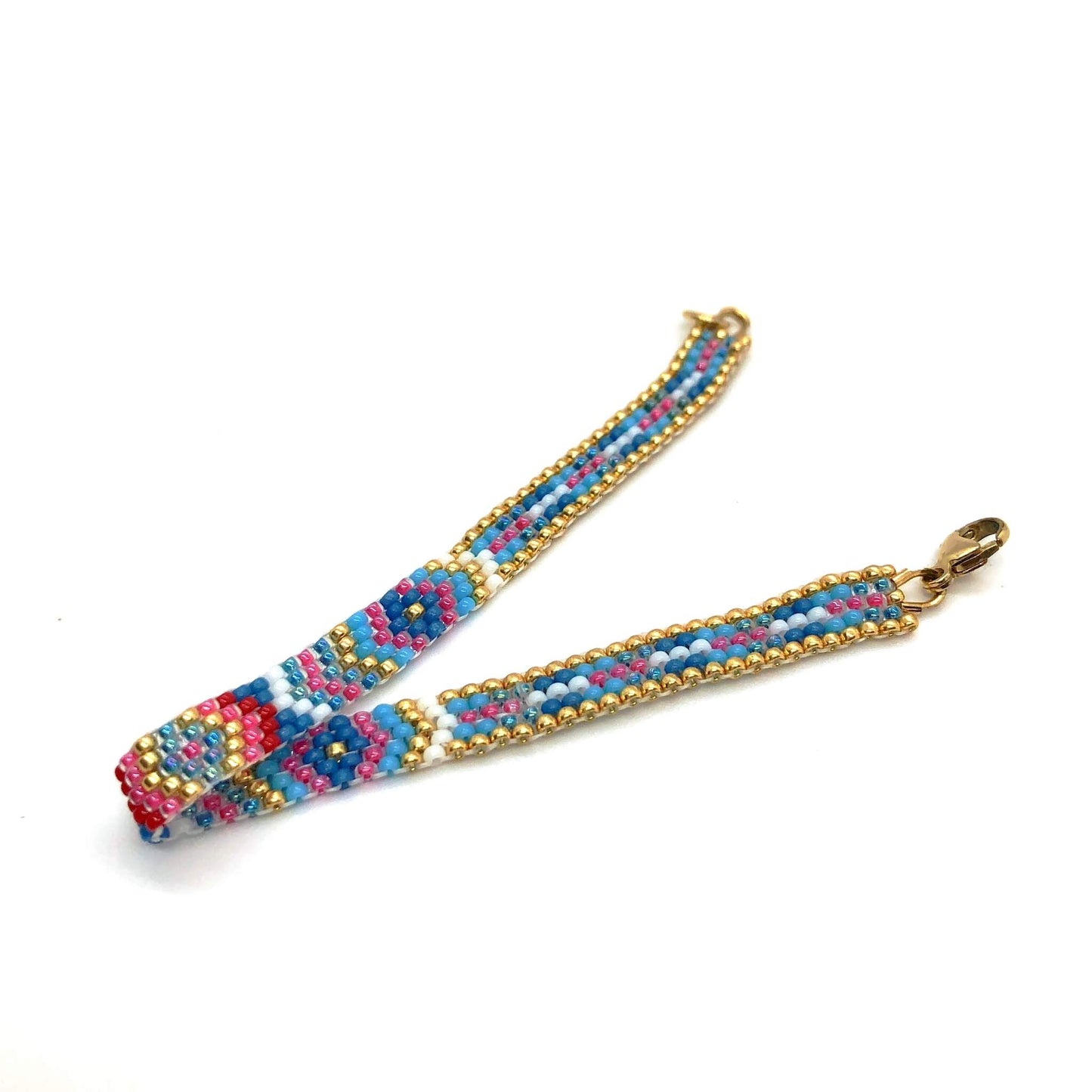 A diamond burst patterned peyote stitch flat beaded bracelet with red, pink, blue, and white seed beads and a gold border.