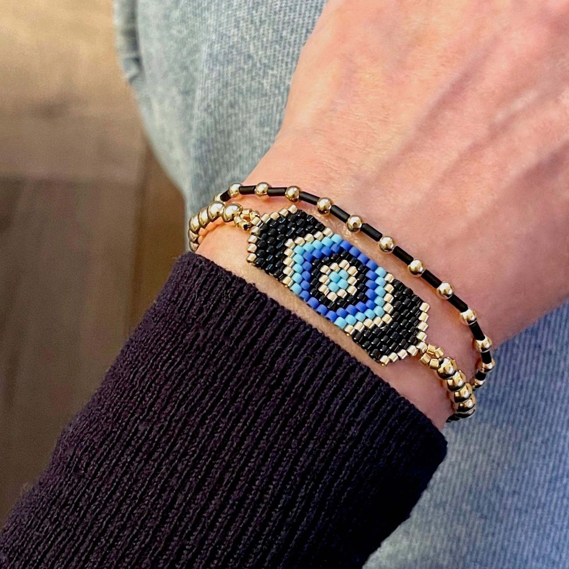 Evil eye stretch bracelet set with black, blue, and gold-tone seed beads and 14K gold filled balls.