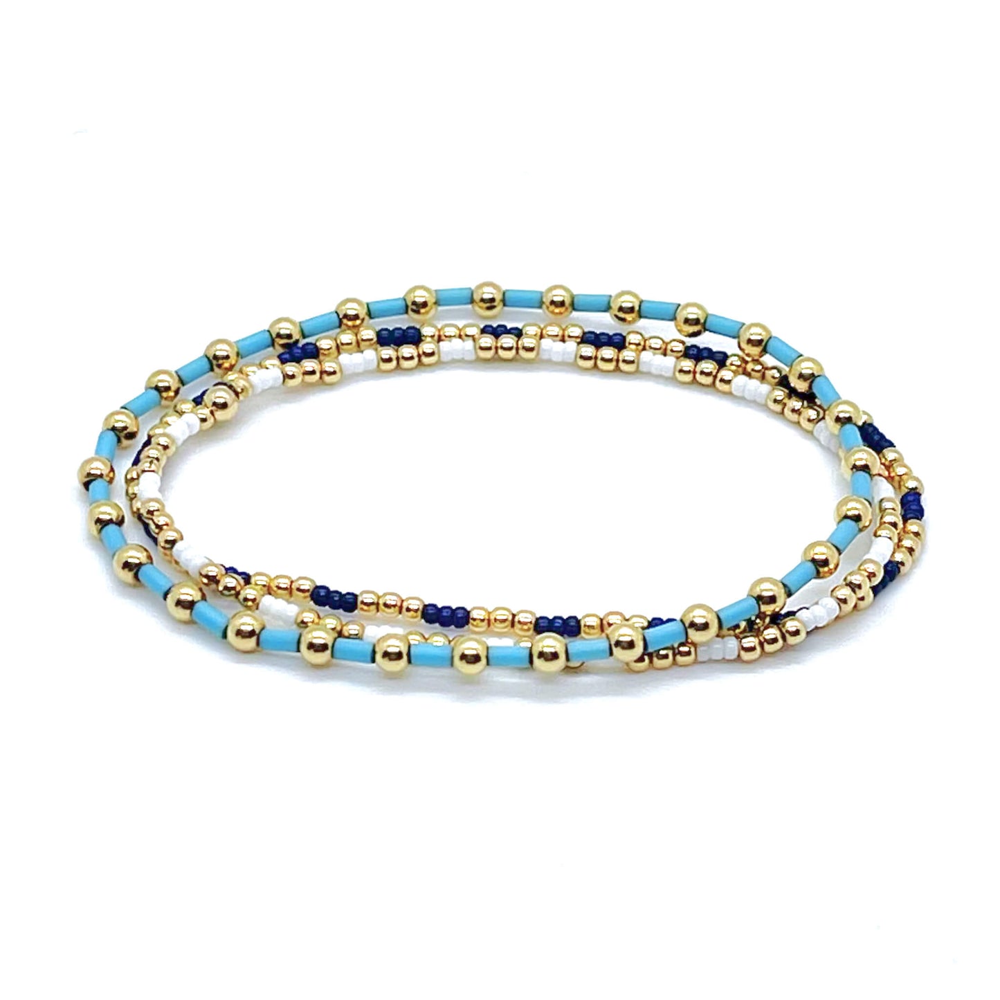 Gold ball bracelets with light blue, white, and navy blue seed beads on elastic stretch. Set of 3.