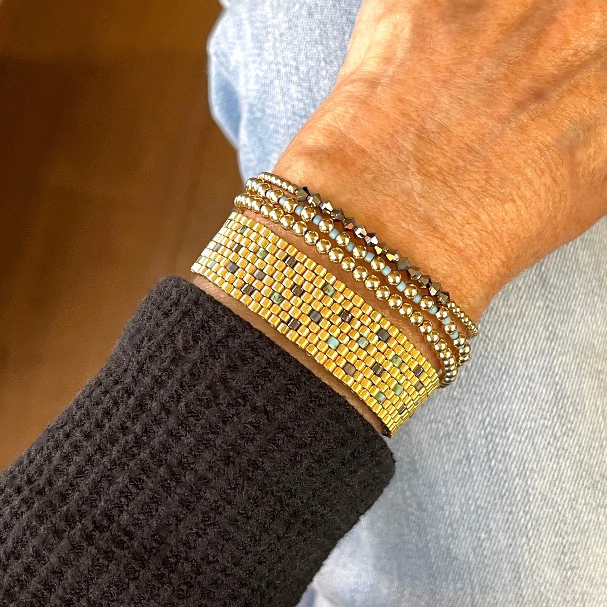 Gold beaded bracelet stack with a handwoven gold seed bead cuff and 3 gold ball stretch bracelets with crystals and seed beads on stretch cord.
