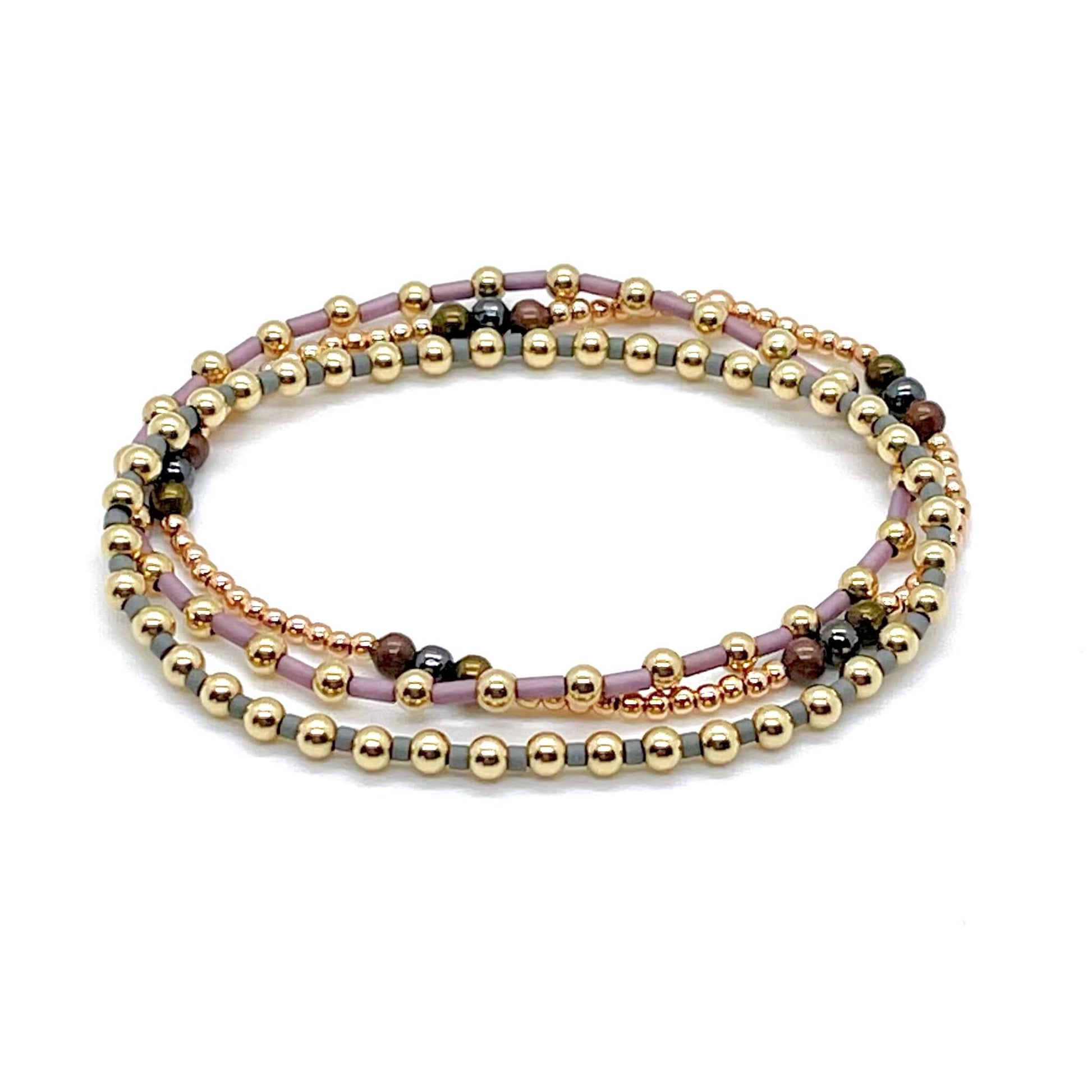Gold beaded stretch bracelet trio with grey, purple, bronze, and gunmetal accent beads. 
