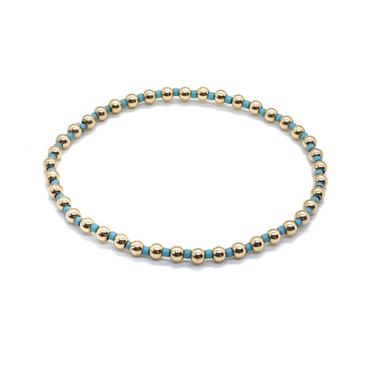 Gold beaded bracelet with alternating turquoise blue seed beads on stretch cord.