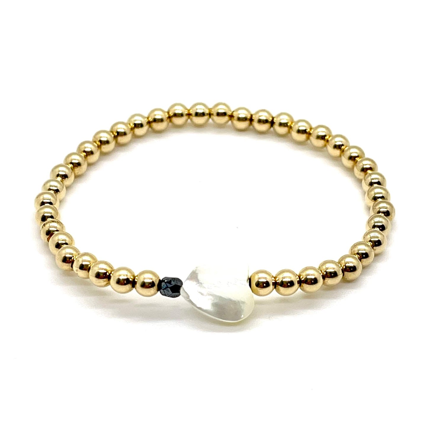 Gold heart bracelet with a mother-of-pearl heart, a small faceted black hemitite crystal, and 4mm 14K gold filled beads.