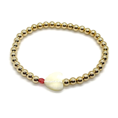 Gold heart bracelet with a mother-of-pearl heart, a small faceted coral-red crystal, and 4mm 14K gold filled beads.