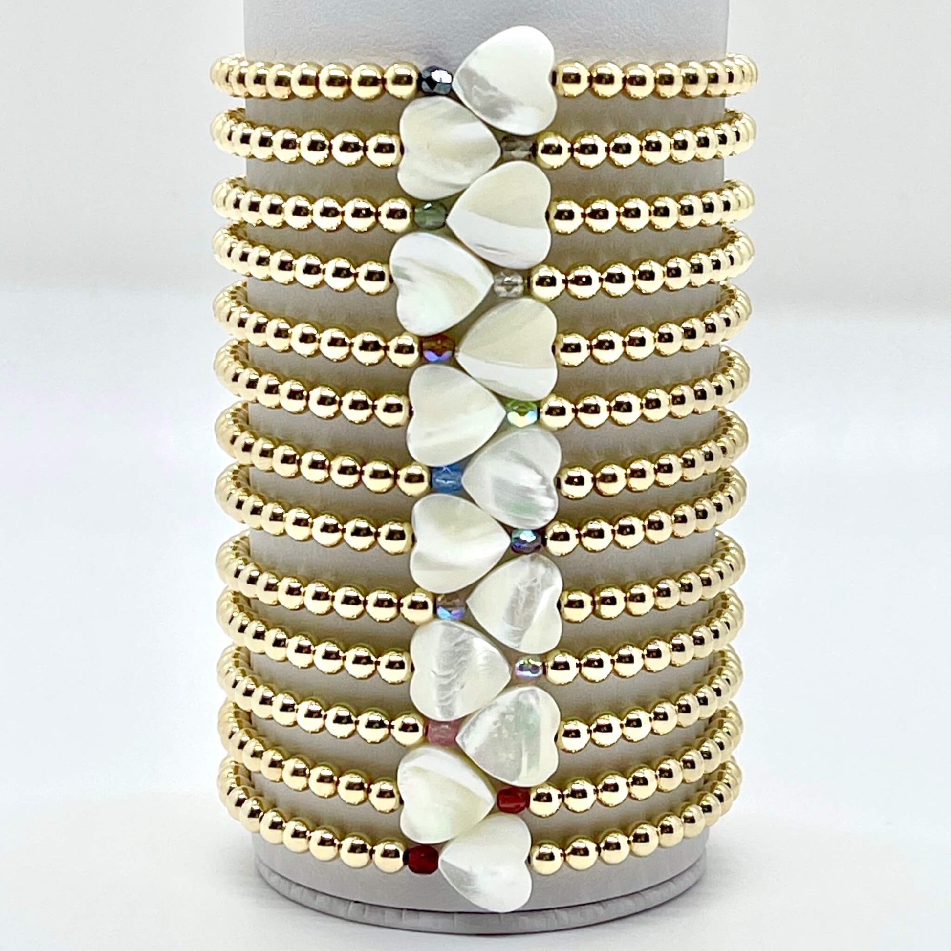 Gold heart bracelets with a mother-of-pearl heart and a small faceted crystal bead in a wide selection of colors.