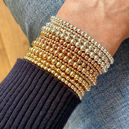 Assorted gold and silver beaded stretch bracelet stack in various sizes ranging from 2mm-4mm ball beads. 