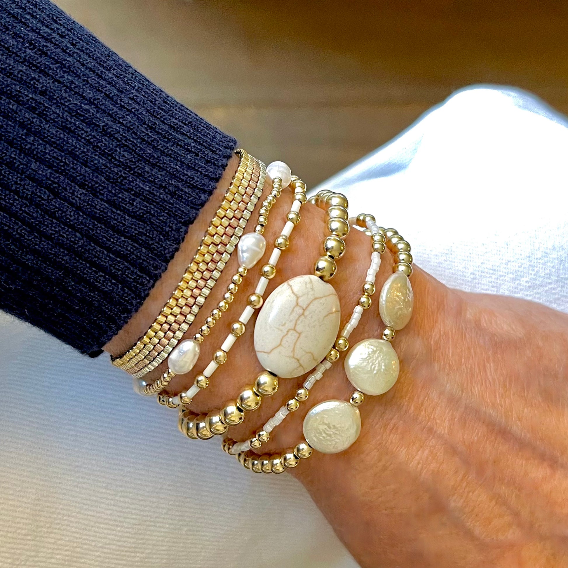 Gold stackable bracelets with freshwater rice and coin pearls, magnesite, and seed beads.