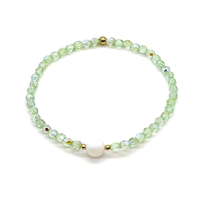 Green crystal bracelet with a mother-of-pearl center bead and small gold accent beads.