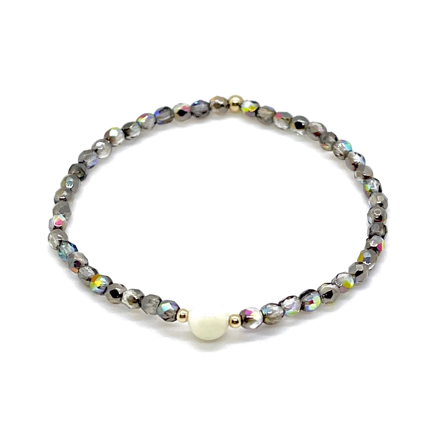 Grey-silver crystal bracelet with mother-of-pearl center bead and small gold accent beads.