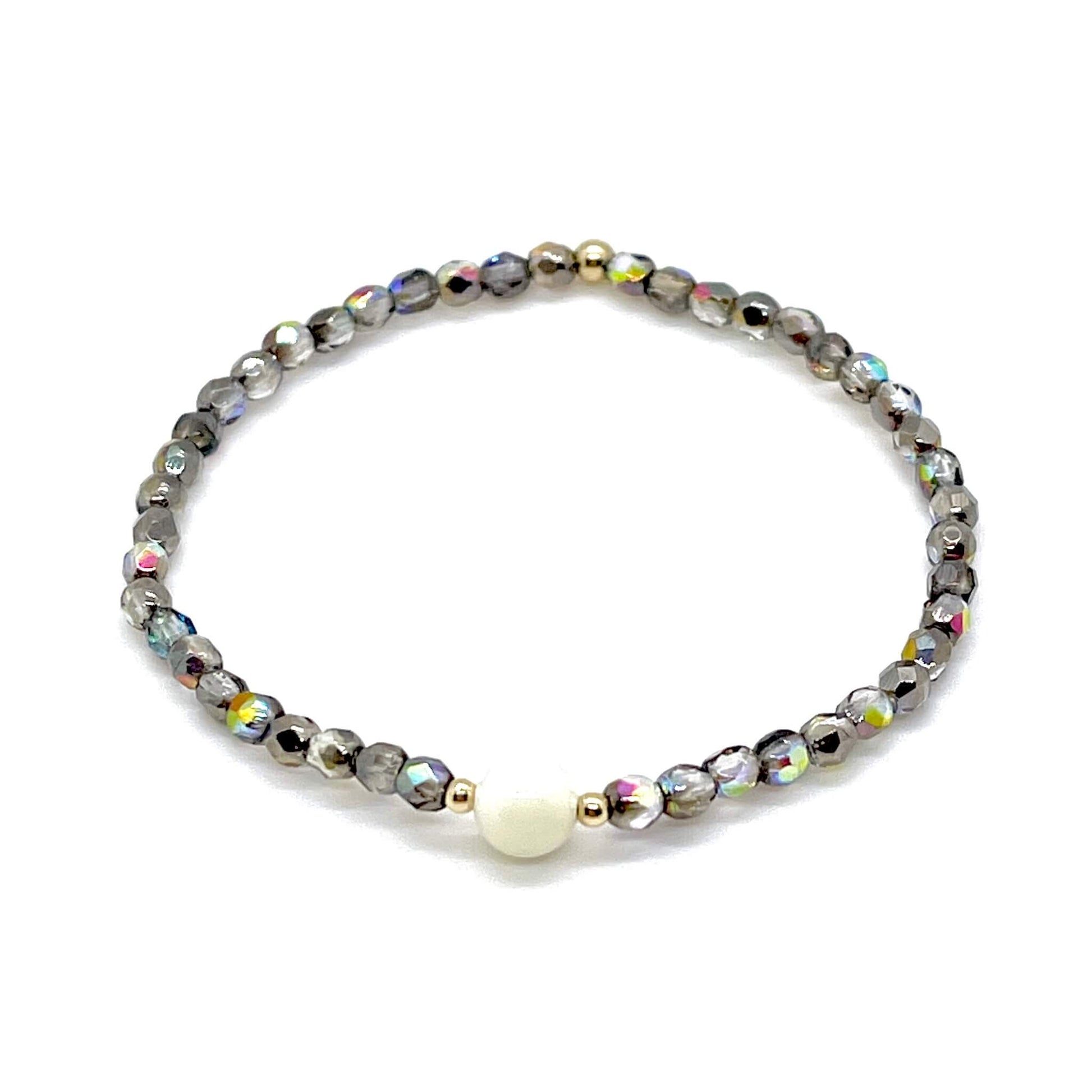 Grey-silver crystal bracelet with mother-of-pearl center bead and small gold accent beads.