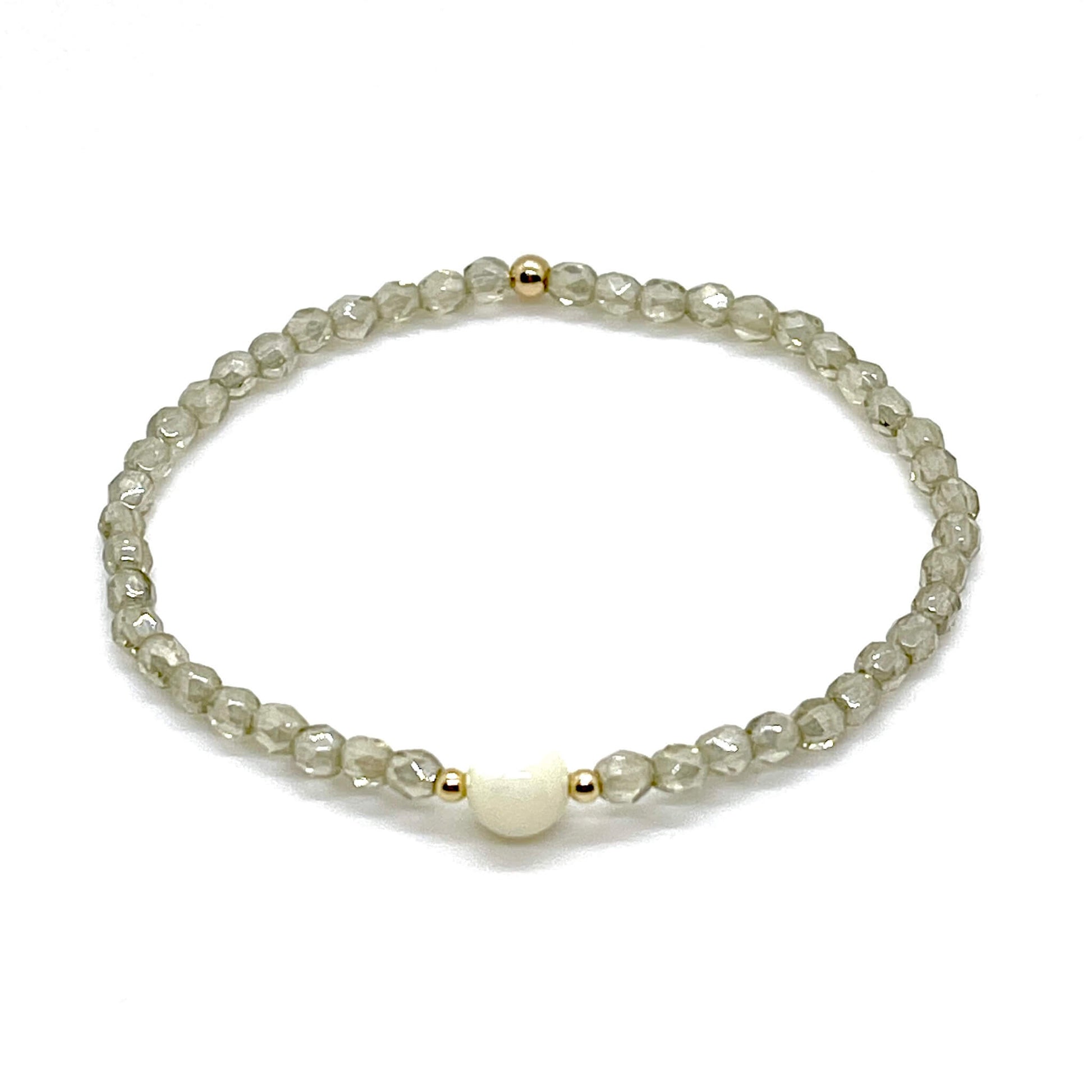 Grey-taupe crystal bracelet with a mother-of-pearl center bead and small gold accent beads.