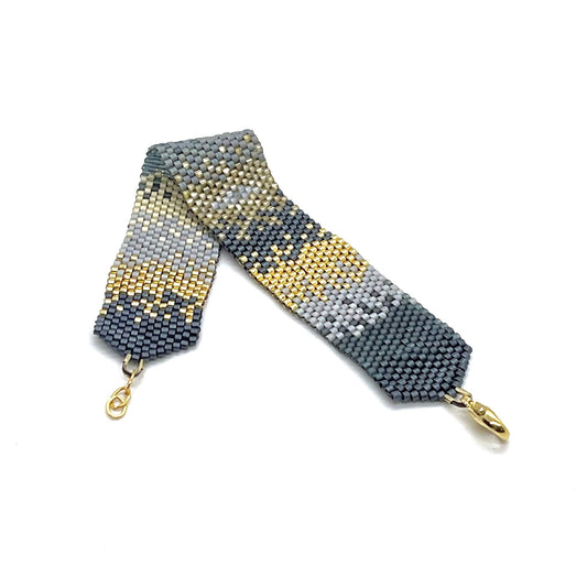 Sleek modern boho handmade beaded bracelet cuff in a slate blue, gray, and gold ombre pattern.