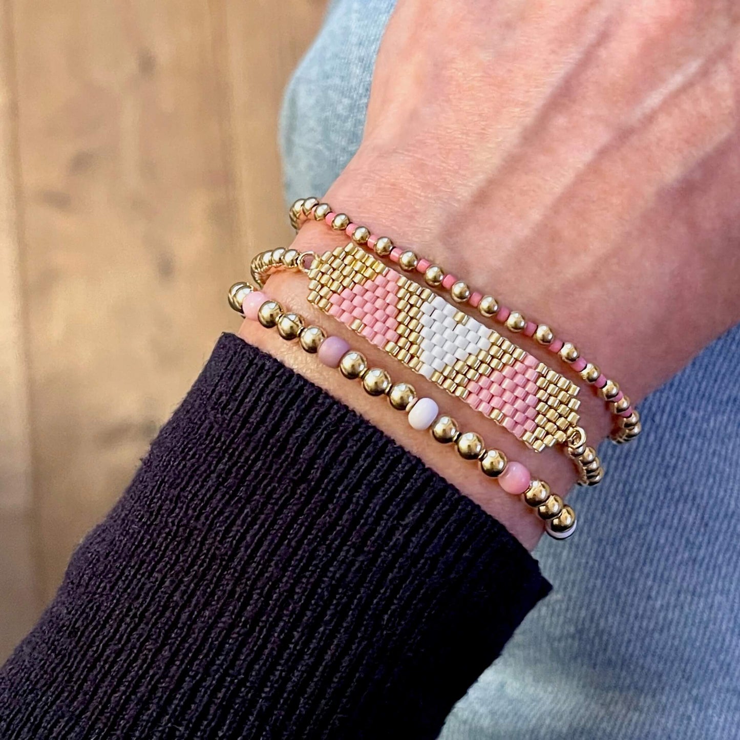 Heart beaded bracelet stack with pink, gold, and white beads.
