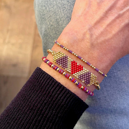 Heart beaded bracelet stack with purple, red, and gold beads.