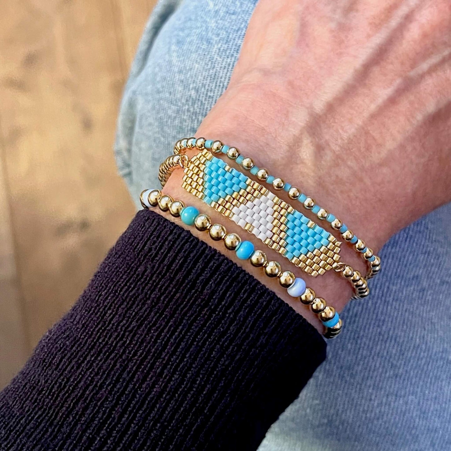 Heart beaded bracelet stack with white, blue, and gold beads.