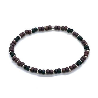 Mens black and brown seed bead bracelet with silver tone accent beads. Thin stretch bracelet with small matte and shiny beads.