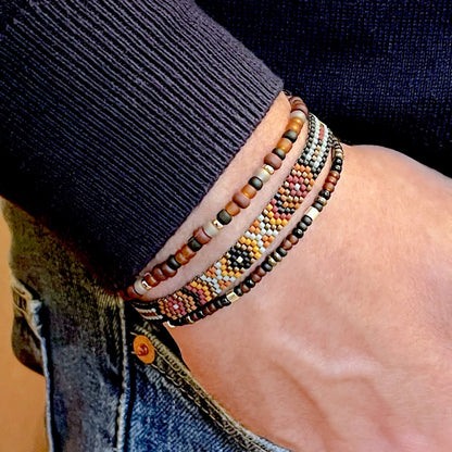 Men’s hand woven beaded brown & gray peyote bracelet layered with brown, amber, black, & pewter seed bead stretch bracelets.