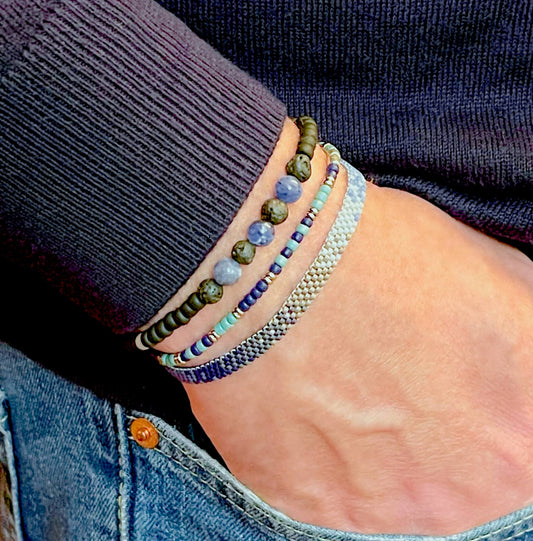 Men’s hand woven blue & gray seed bead ombre peyote bracelet stack with sodalite, black lava, blue, & gray beaded stretch bracelets.