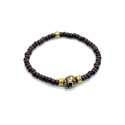 Men's skull bracelet with antique brass-plated skull and accent beads, and matte brown seed beads on elastic stretch cord.
