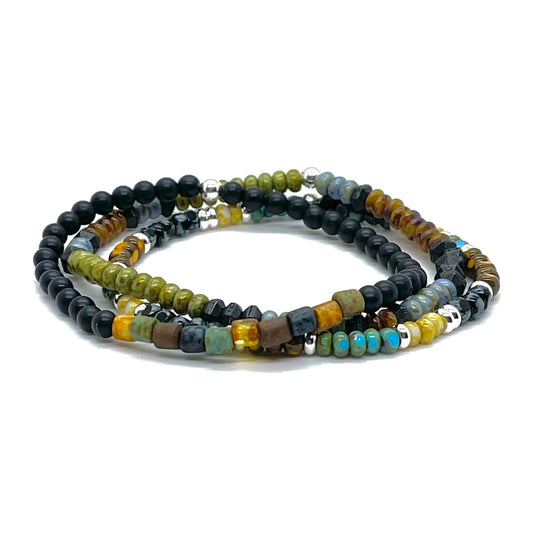 Minimalist beaded bracelet stack with earth-tone seed beads and black onyx, pewter, and silver-plate beads.