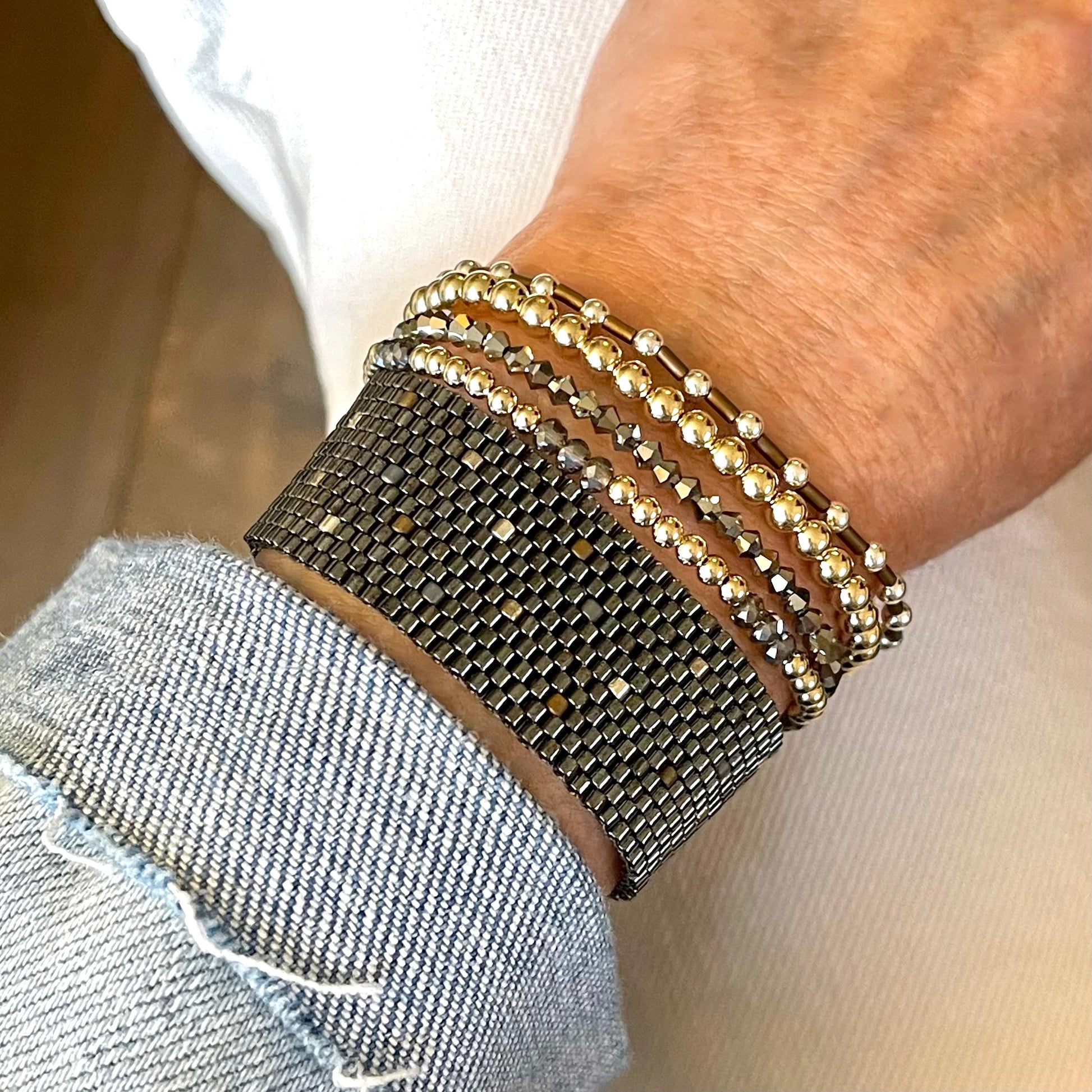 Mixed metal stretch bracelet stack with gunmetal woven beaded cuff band.