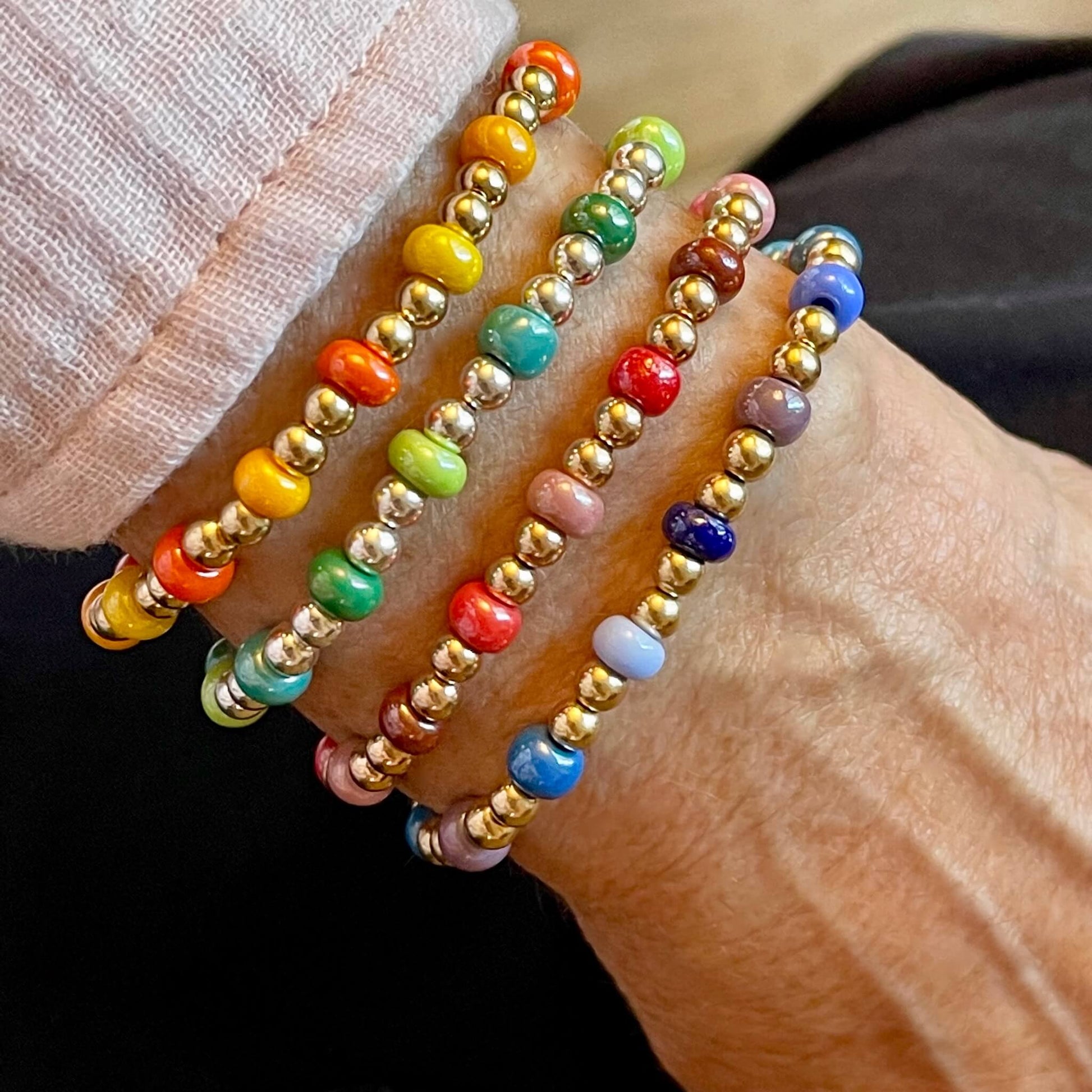Stacking bracelets with gold fill & sterling silver ball beads, and orange, yellow, green, red, pink and blue accent beads.