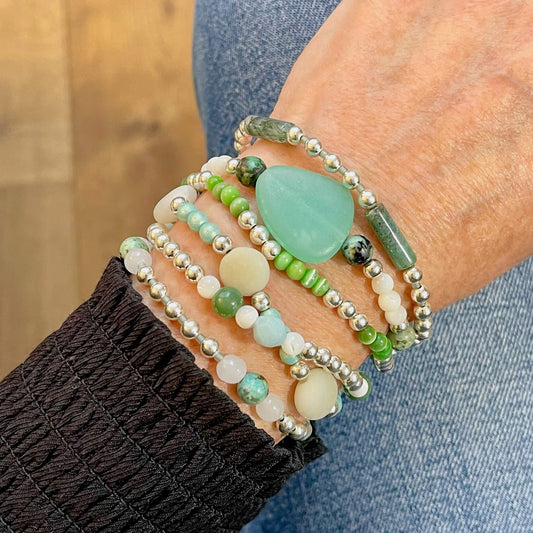 Multi strand wrap bracelet with silver beads and white and green glass, mother of pearl, and stone beads.