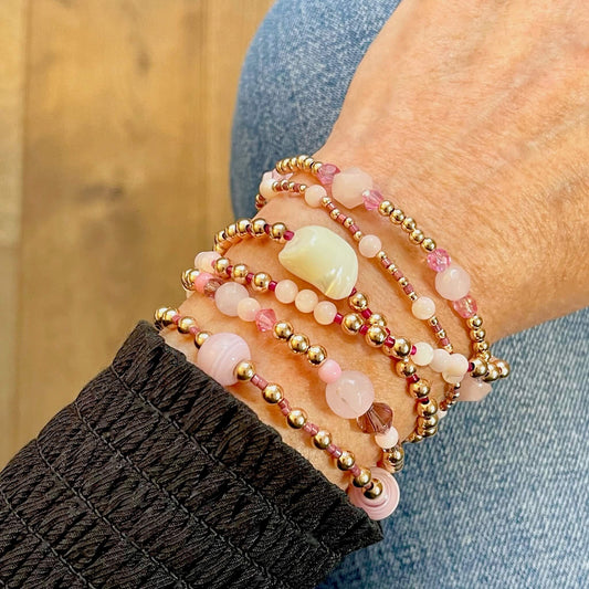 Multi strand wrap bracelet  with gold beads, mother of pearl, and pink glass and seed beads. Wraps wrist 6 times on elastic.