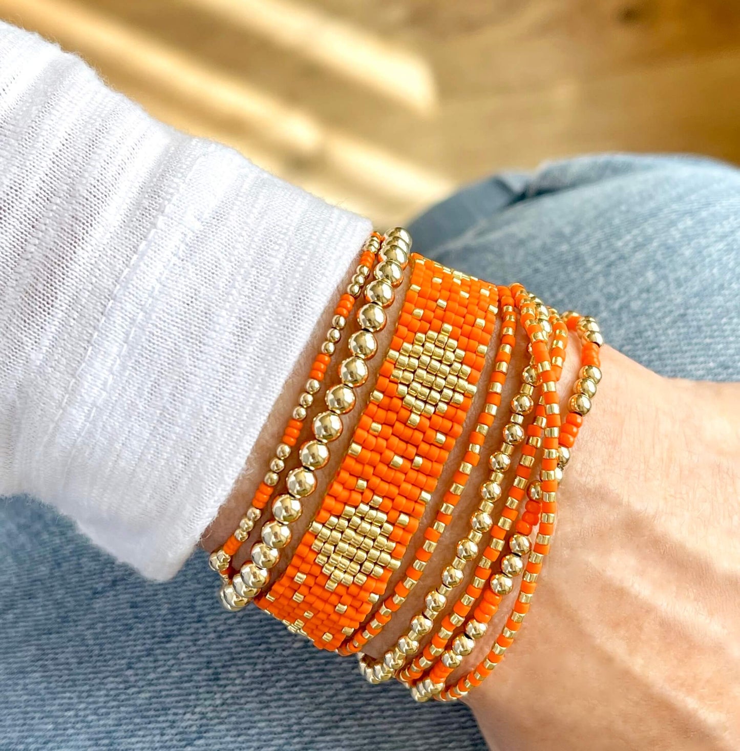 Orange bracelets with a handwoven seed bead cuff and wrap, and 14K gold filled round bead stretch bracelets.
