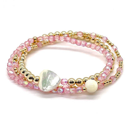 Pink crystal and gold bracelet stack of 3. Womens handmade stretch bracelets wtih round and heart shaped mother-of-pearl accent beads.
